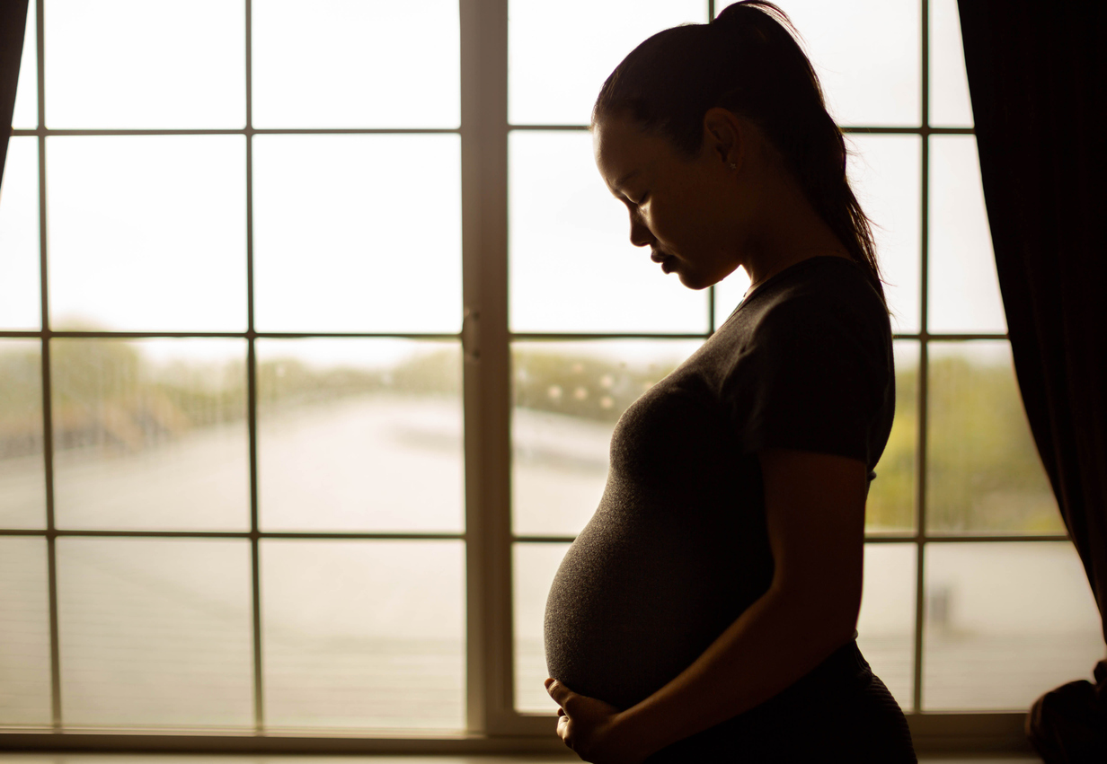 Pregnant woman standing by window.